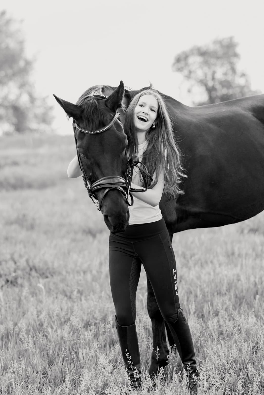 Young woman laughing with horse