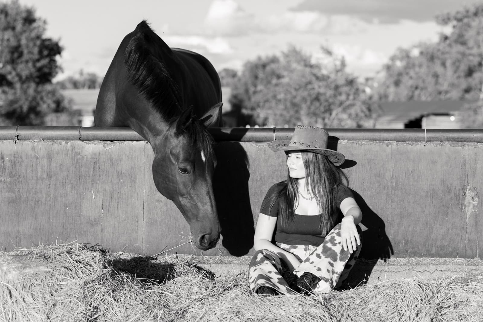 Woman with cowboy hat sitting with horse