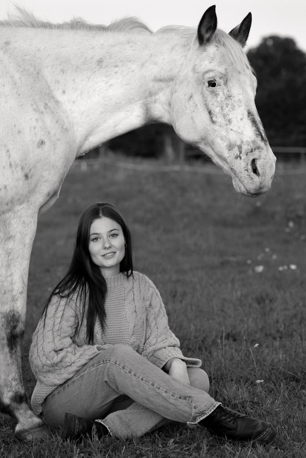 Woman sitting under white horse