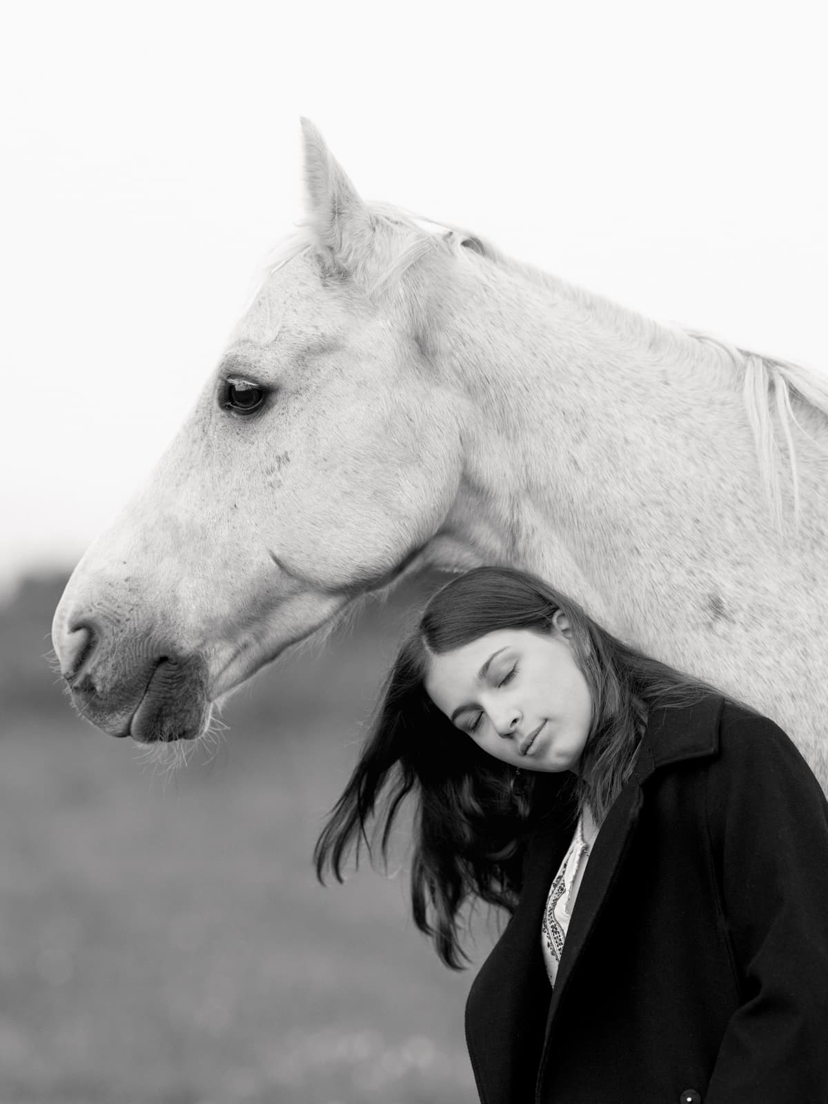 Woman leaning against white horse