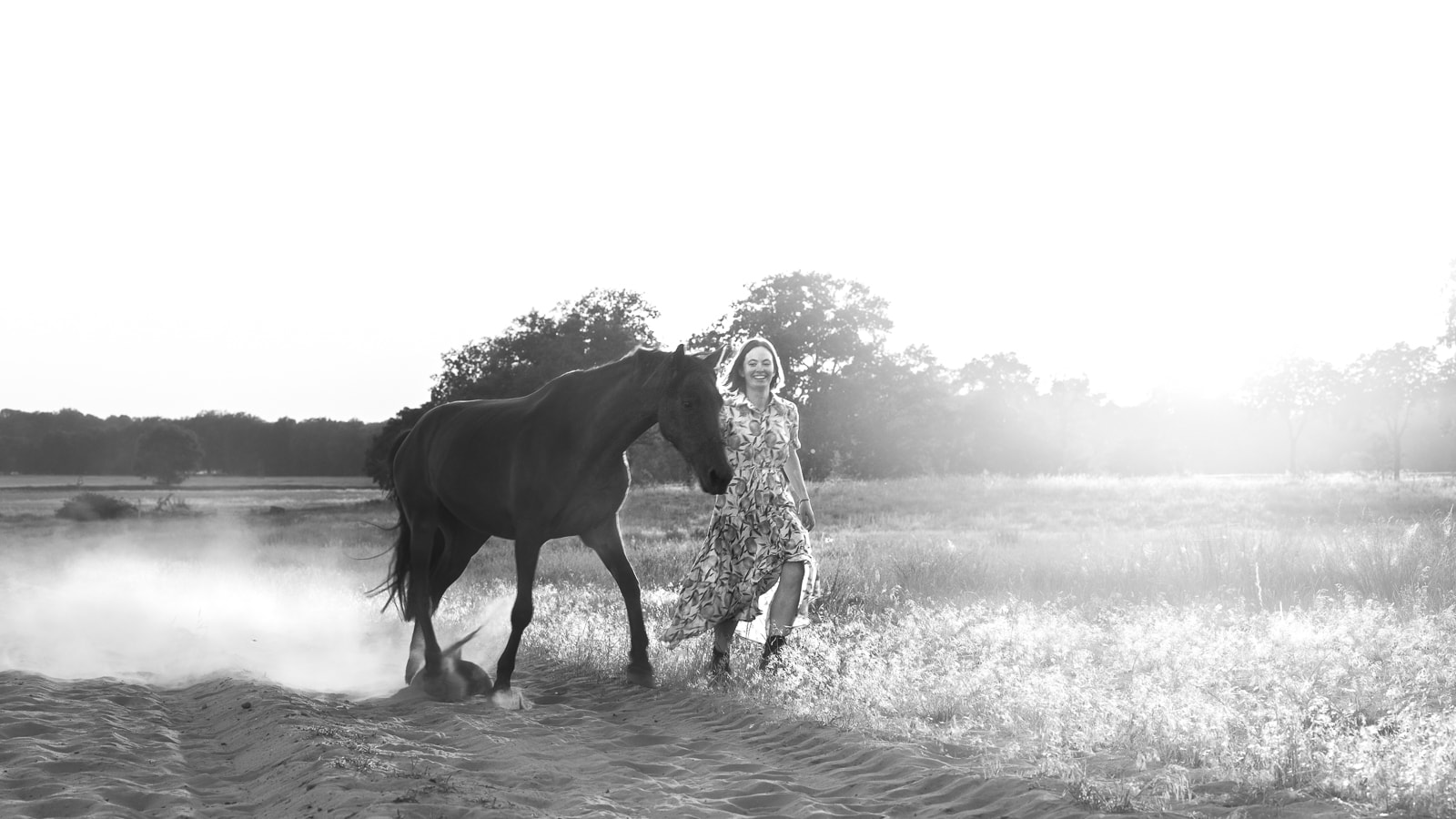 Woman and horse in intimate moment in backlight, artistic black and white portrait