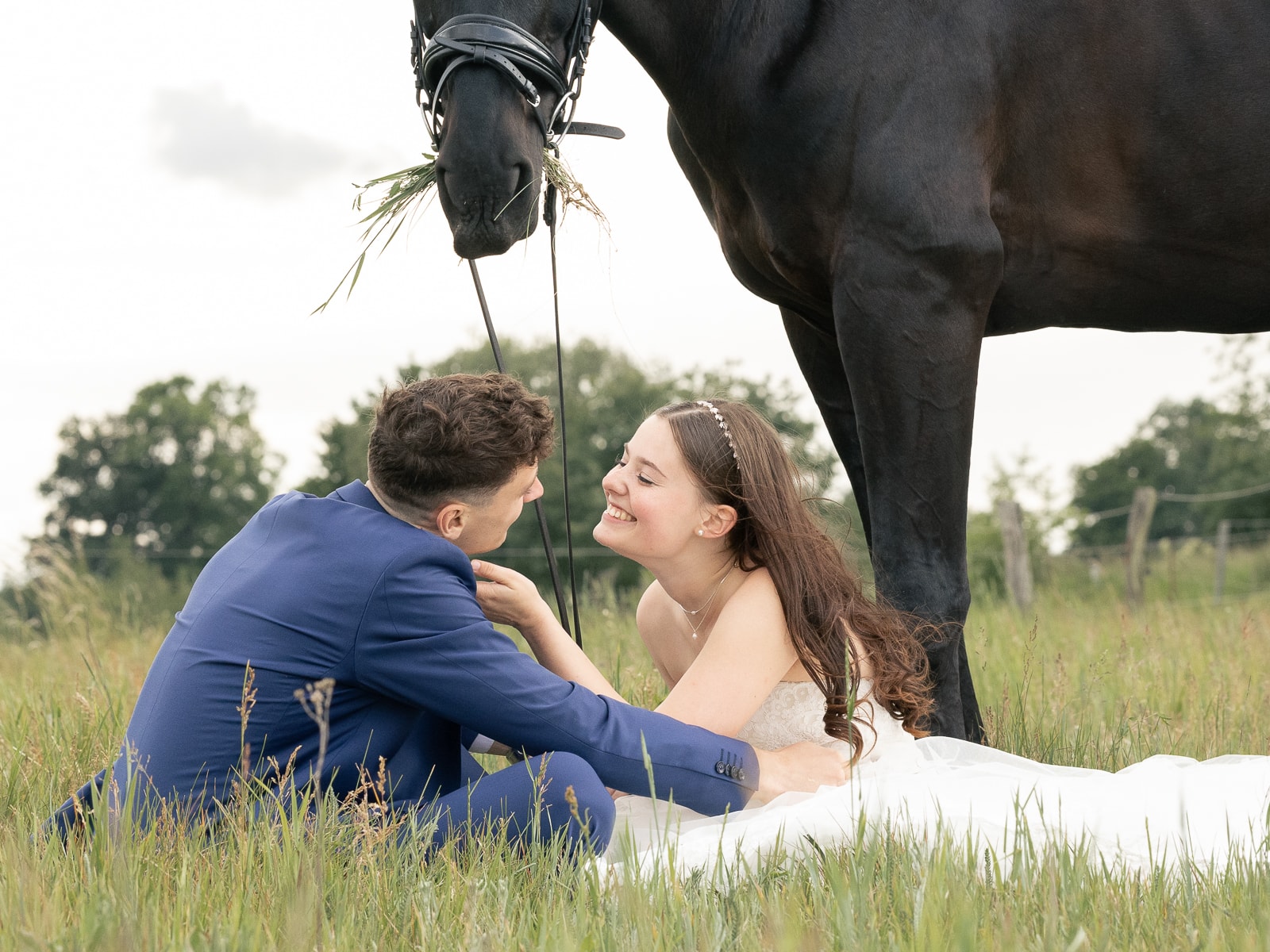 Wedding couple embracing intimately with curious horse