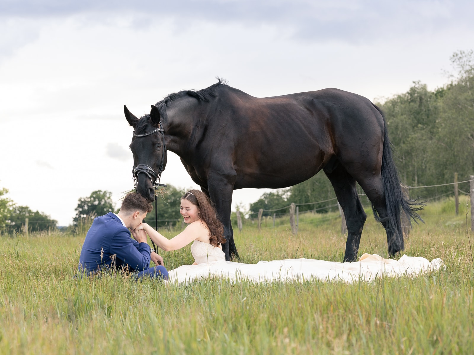 Wedding couple sitting relaxed with horse on meadow